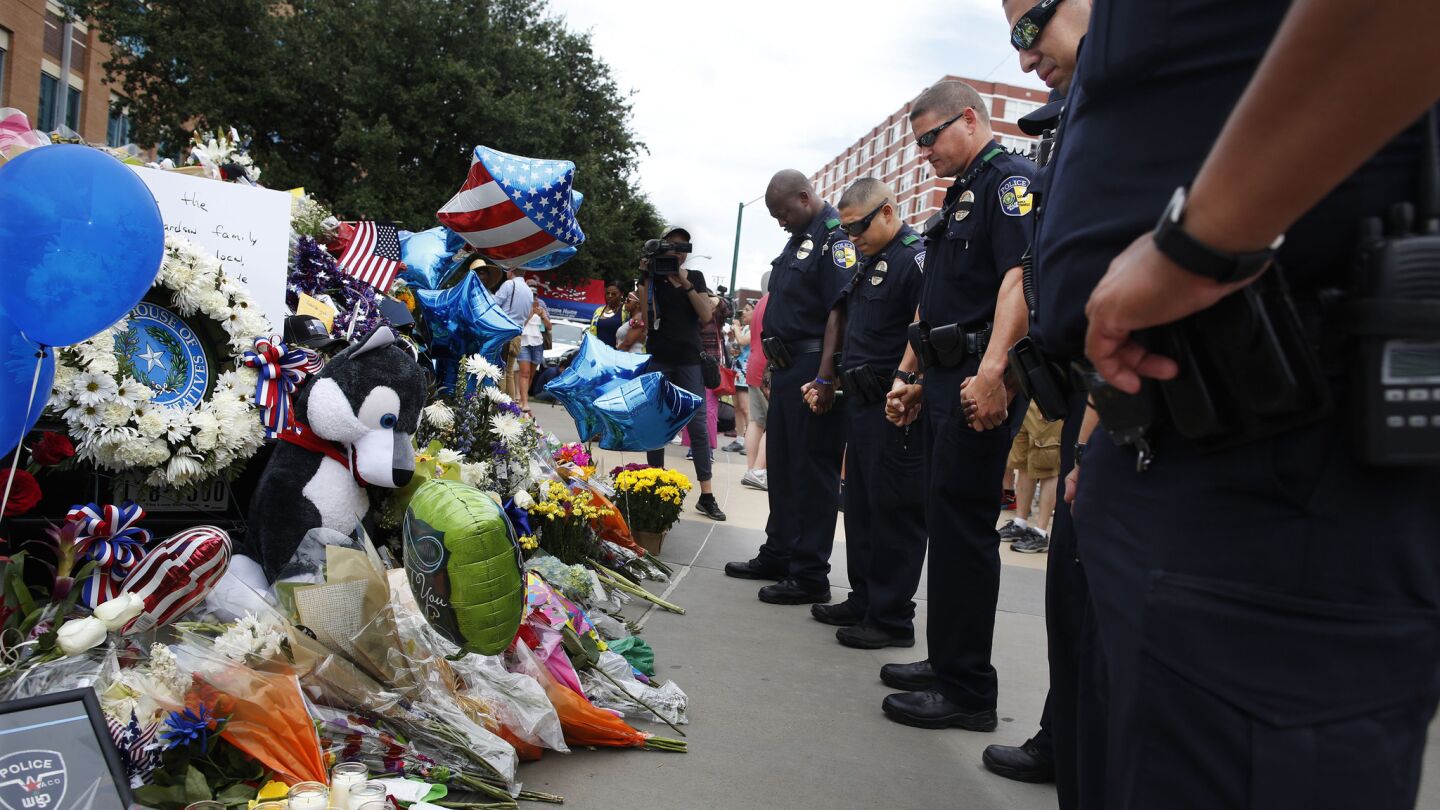 DART Police officers pray in front of the Dallas police headquarters on Saturday.