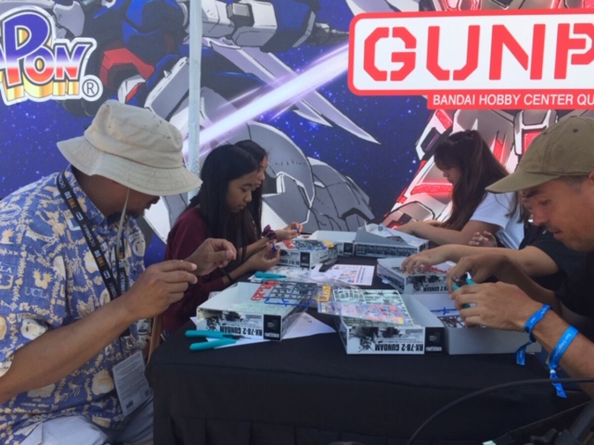 A family builds free Gundam models at the Petco Park Interactive Zone, in the Lot near Petco Park through Sunday