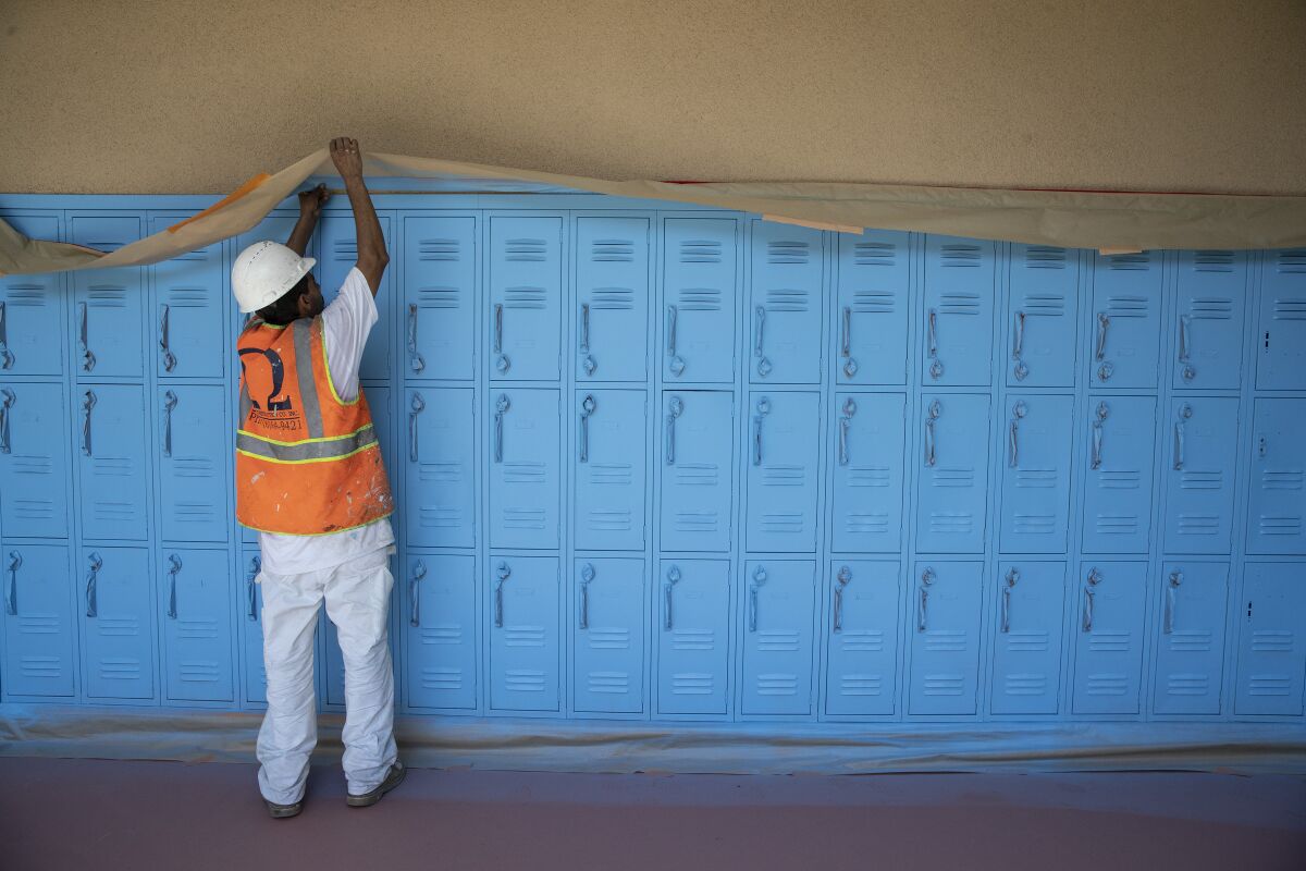 Painting contractor Jose Ortiz works on a hall of lockers at Oliver Wendell Holmes Middle School on Aug. 18 in Northridge.