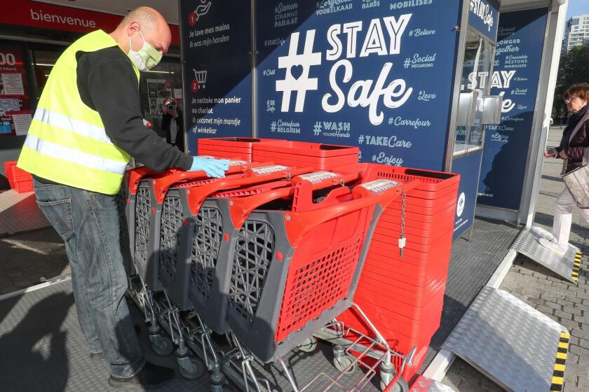 A member of staff arranges shopping carts at a "disinfectant unit" of a supermarket in Brussels on April 10, 2020, as Belgium is in its fourth week of confinement in the ongoing coronavirus crisis.