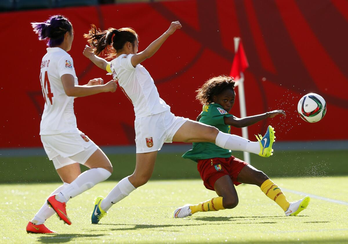 Wu Haiyan and Zhao Rong of China try to block a shot from Gabrielle Onguene of Cameroon during a Round of 16 match at the Women's World Cup.