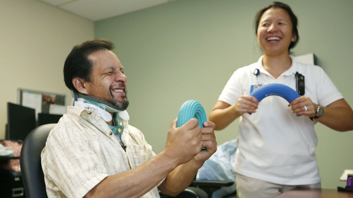 Victor Espinoza works with occupational therapist Lily Guerrero during a physical therapy session.