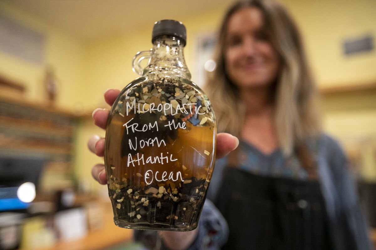 Jessica Walden holds a bottle of microplastic she pulled from Atlantic Ocean in her shop Amis de la Terre Zero-Waste Market.