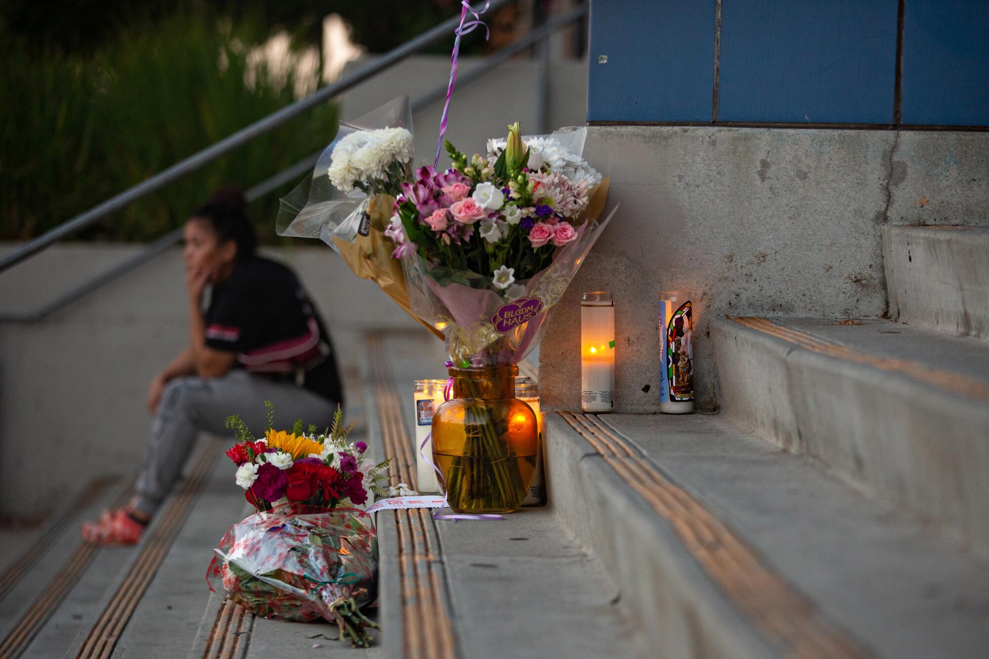 A memorial with flowers and candles on the steps of a high school