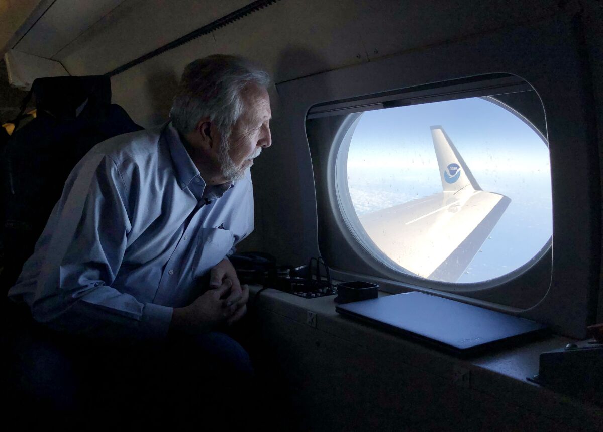 A man sits looks out an airplane window.