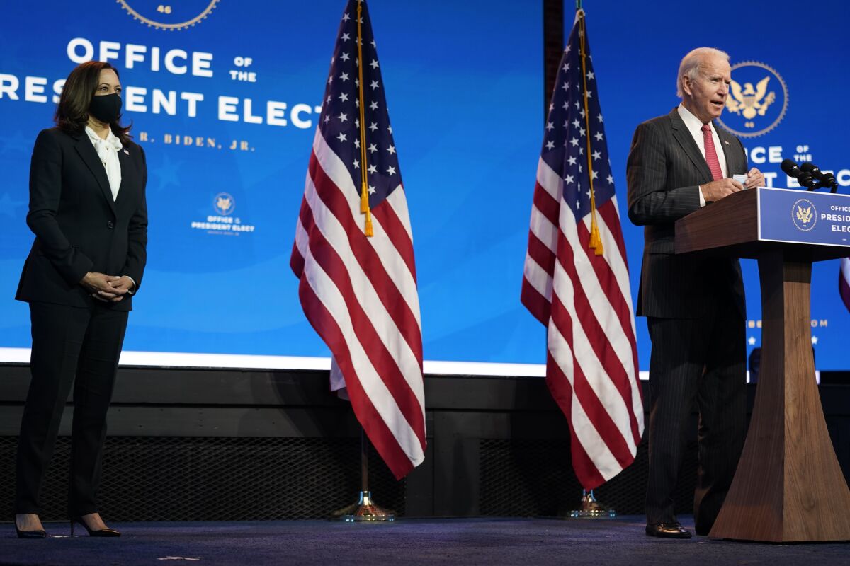 President-elect Joe Biden, standing near Vice President-elect Kamala Harris, speaks at a podium