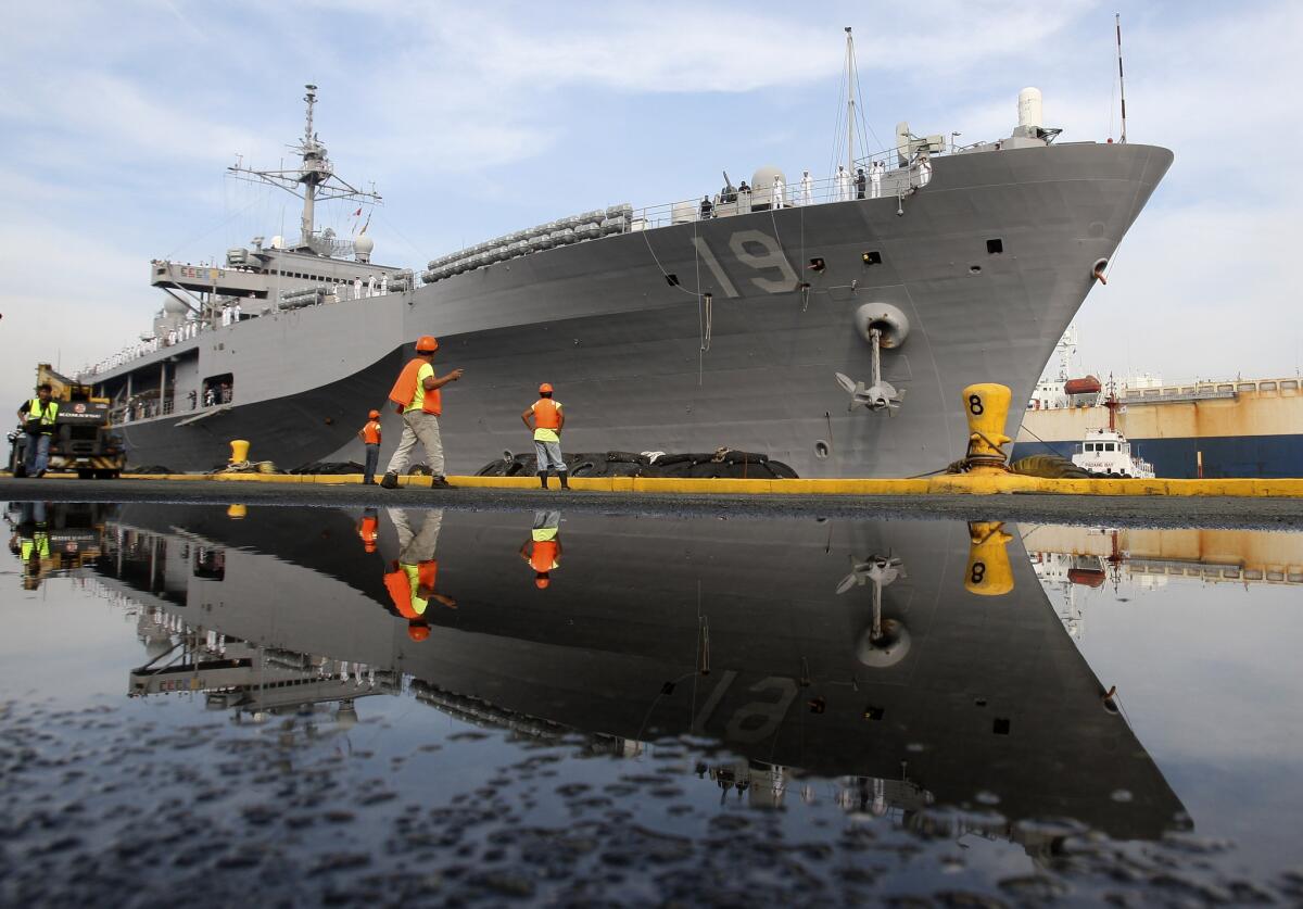 Port workers in Manila prepare the docking of the Blue Ridge, the flagship of the U.S. Navy's 7th Fleet.