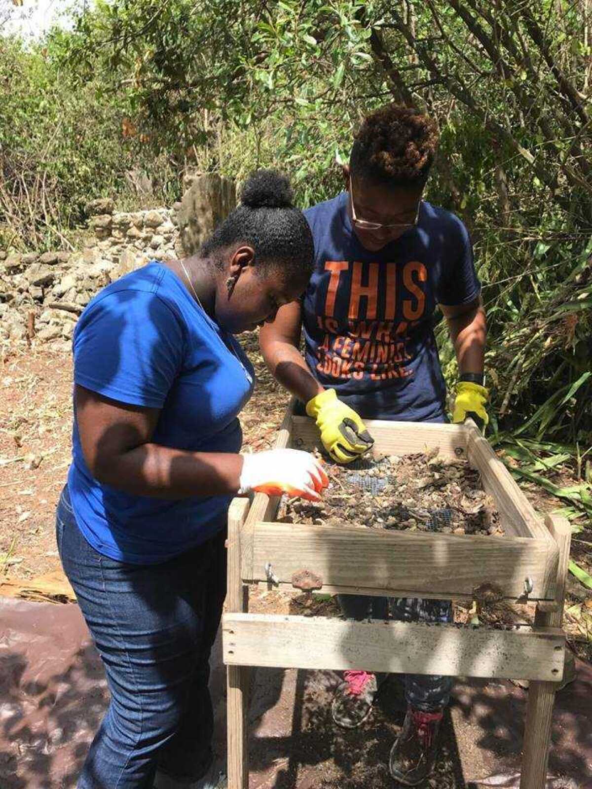 Ayana Omilade Flewellen, left, works alongside a participant in a youth archaeology program