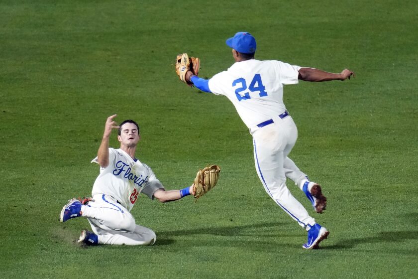 Florida infielder Josh Rivera (24) makes the catch on a South Carolina pop fly as outfielder Richie Schiekofer slides to avoid a collision during the fifth inning of an NCAA college baseball tournament super regional game Friday, June 9, 2023, in Gainesville, Fla. (AP Photo/John Raoux)