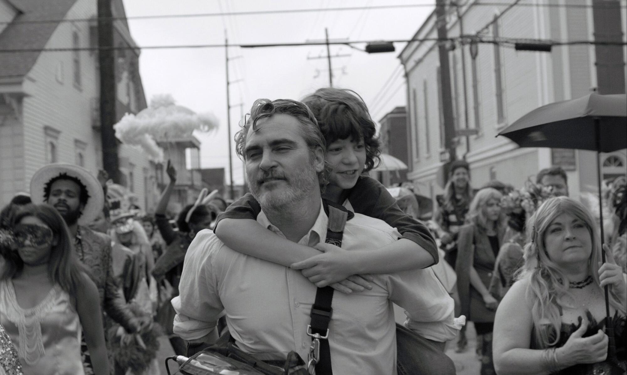 A black-and-white photo of a man giving a boy a piggyback ride 