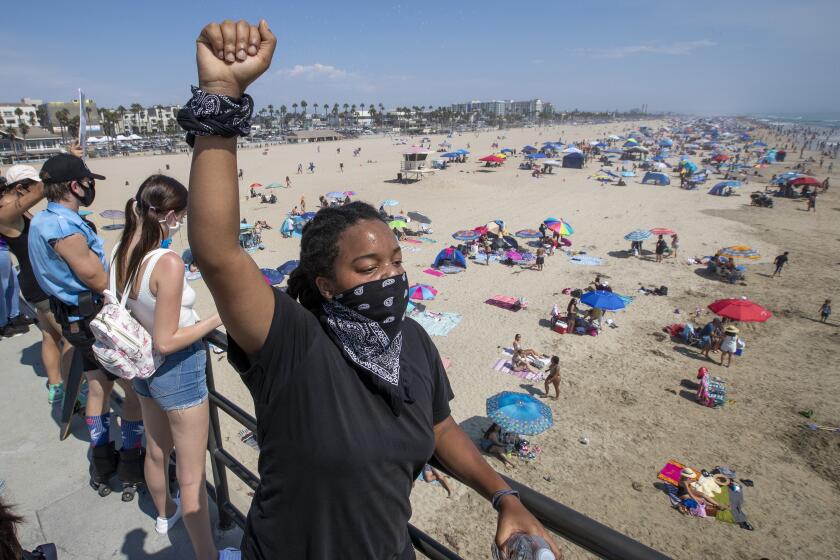 HUNTINGTON BEACH, CA - SEPTEMBER 06: Black Lives Matter supporter Mari Drake, of Los Angeles, raises her fist in the air as she joins protesters marching down the Huntington Beach pier in protest of justice for George Floyd and against the deaths of numerous other African Americans by police actions in Pier on Sunday, Sept. 6, 2020 in Huntington Beach, CA. Members of the groups Black Unity, Dope Movement also participated to show support for Queer Black Lives and All Black Lives Matter. (Allen J. Schaben / Los Angeles Times)
