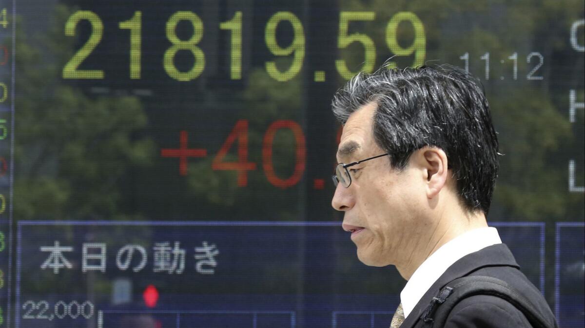 A man walks by an electronic stock board of a securities firm in Tokyo.