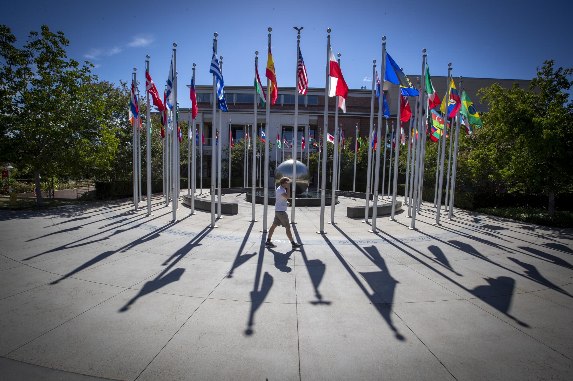 A pedestrian walks past flagpoles at Chapman University in Orange. 