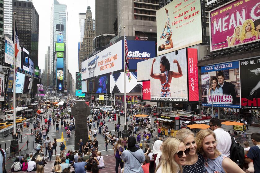 FILE - In this June 20, 2019, file photo, tourists visit Times Square in New York. After three months of a coronavirus crisis followed by protests and unrest, New York City is trying to turn a page when a limited range of industries reopen Monday, June 8, 2020. (AP Photo/Mark Lennihan, File)