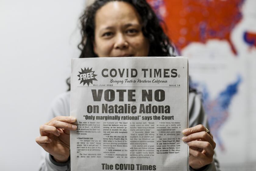 Nevada City, CA, Monday, June 6, 2022 - Assistant County Clerk, Recorder of Nevada County Natalie Adona is running for County Clerk and has been targeted with apparently racist attack ads from her opponent Paul Gilbert, a self-titled election auditor who is concerned the voting system is susceptible to cheating. She holds up a new copy of the Covid times that emphatically tells readers to vote against her. (Robert Gauthier/Los Angeles Times)