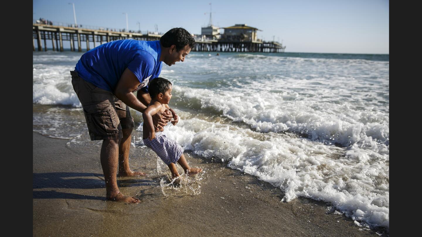Nagendra Tiruttani brings his son, Rishi, 2, up to the water as they visit the beach in Santa Monica.