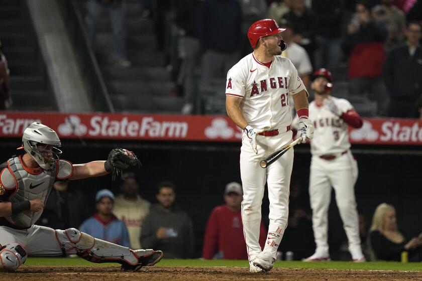 Mike Trout, centro, de los Angelinos de Los Ángeles, reacciona después de ser ponchado para terminar el juego de béisbol mientras el receptor de los Orioles de Baltimore, James McCann, izquierda, se hinca detrás del plato, el lunes 22 de abril de 2024, en Anaheim, California. (AP Foto/Mark J. Terrill)