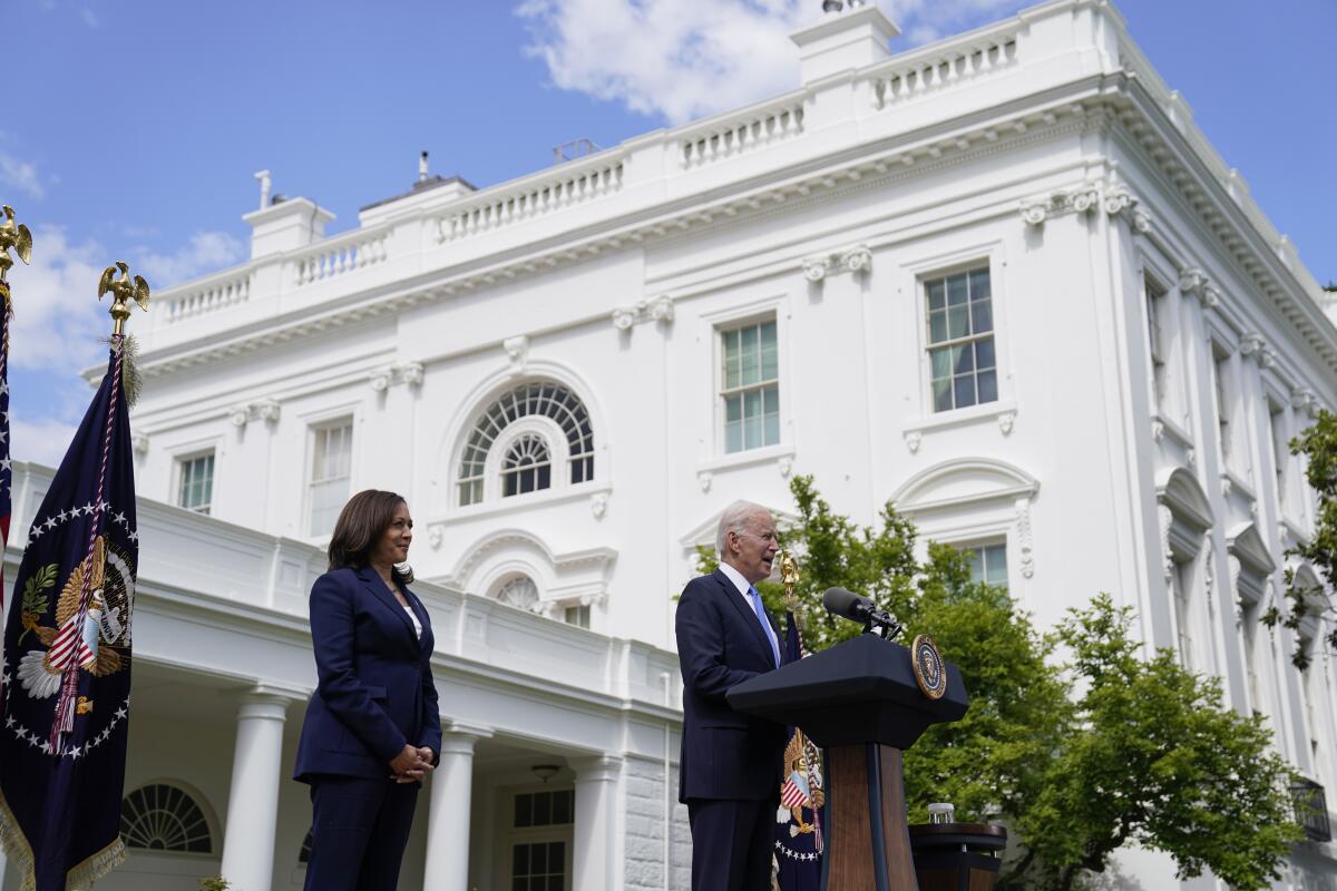 FILE - In this May 13, 2021, file photo Vice President Kamala Harris listens as President Joe Biden speaks on updated guidance on face mask mandates and COVID-19 response, in the Rose Garden of the White House in Washington. The Centers for Disease Control and Prevention said Thursday that fully vaccinated people — those who are two weeks past their last required dose of a COVID-19 vaccine — can stop wearing masks outdoors in crowds and in most indoor settings. Across Washington, the government is adjusting in a variety of ways to new federal guidance easing up on when face masks should be worn. (AP Photo/Evan Vucci, File)