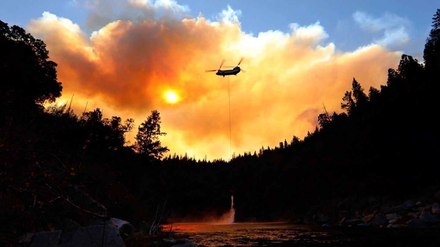 Outside of Pulga, Calif., on the North Fork of the Feather River, where the Camp fire may have started, helicopters do airdrops while ground crews try to keep the fire from spreading.