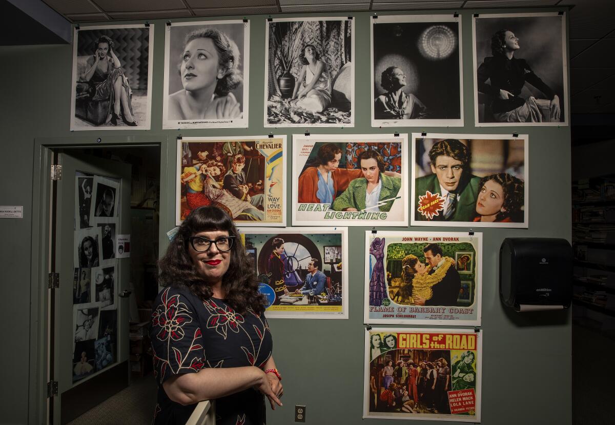 A woman stands next to a wall covered in photos.