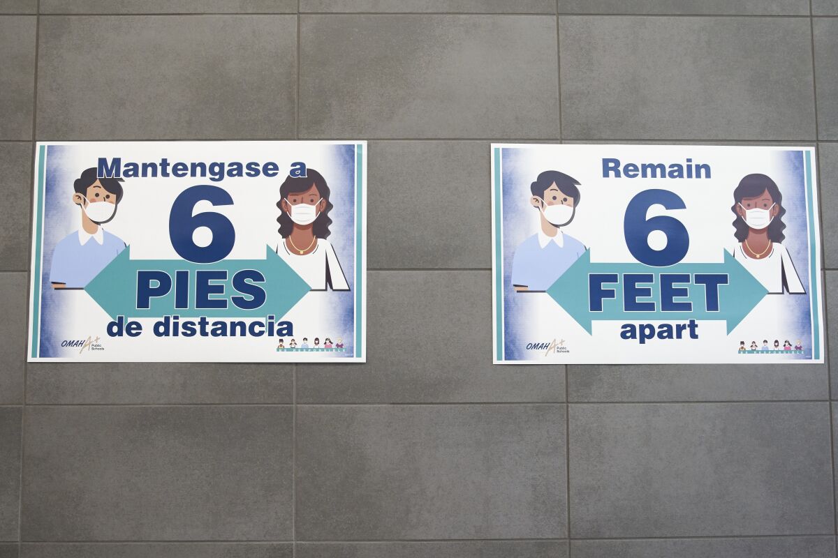 ARCHIVO - Dos letreros piden a la gente mantener una distancia de 1,8 metros (6 pies) entre sí 