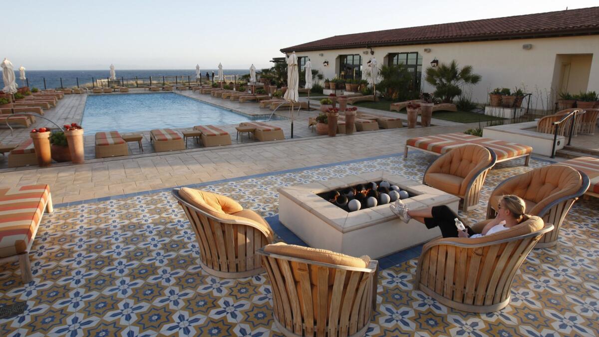 A woman relaxes by the fire pit overlooking the swimming pool and ocean at sunset at the Terranea Resort in Rancho Palos Verdes. Unite Here Local 11 is intensifying its call for a boycott of the resort over allegations of sexual assaults on workers.