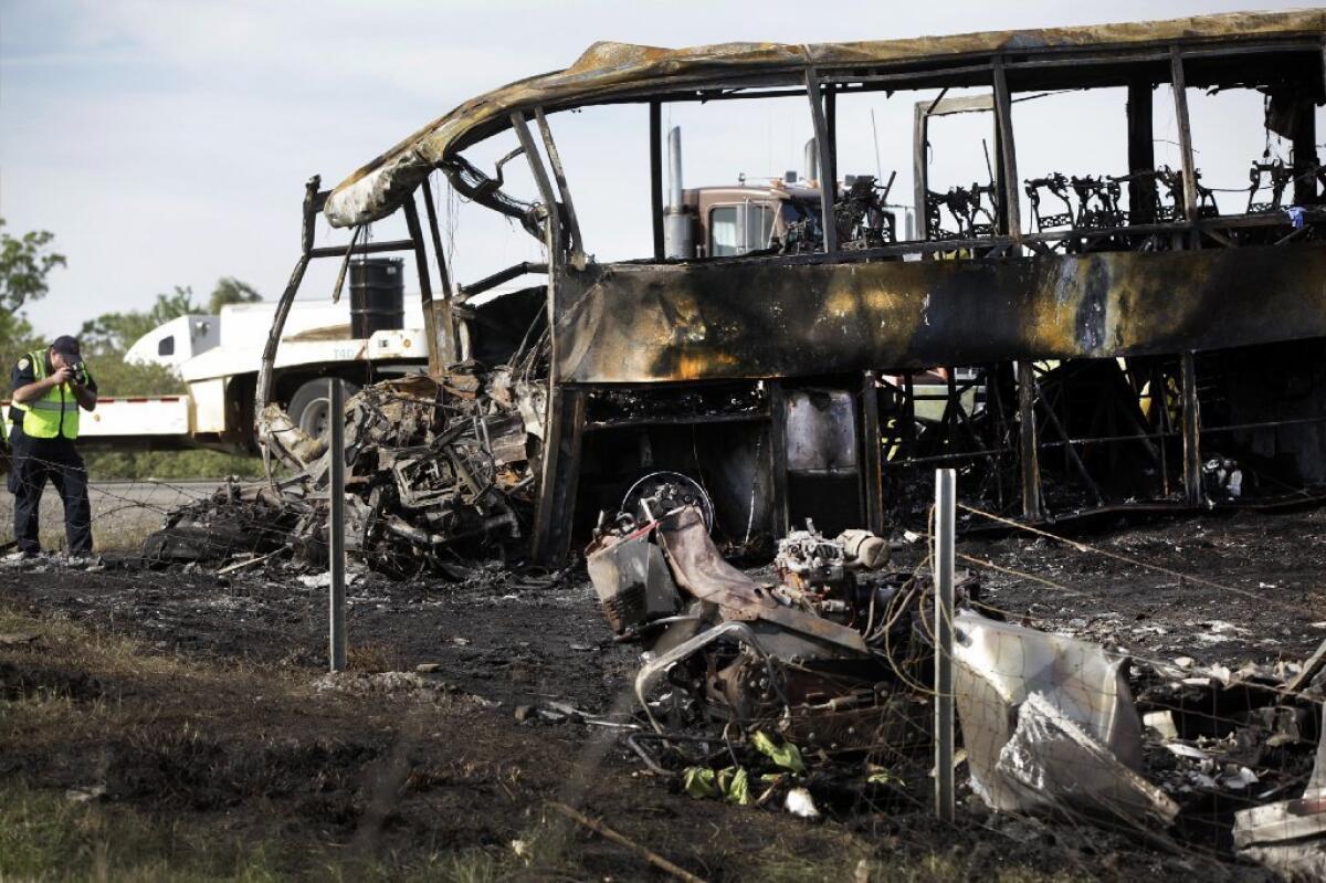 A police photographer takes pictures at the scene of a fiery collision between a FedEx truck and a tour bus Thursday on Interstate 5 near Orland, Calif., that killed 10 people.