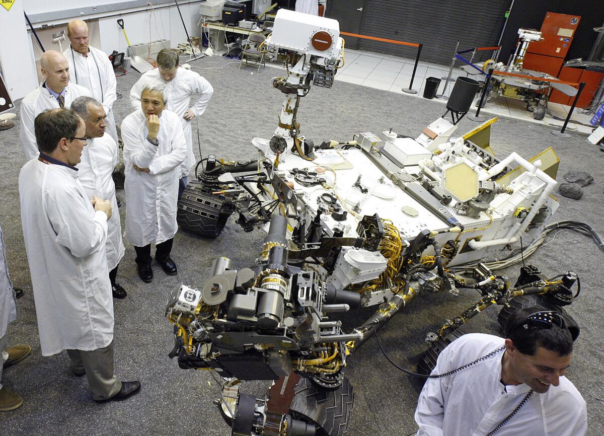 NASA Administrator Charles Bolden talks with scientist and engineers at JPL next to a duplicate of the Mars Rover Curiosity at JPL on Wednesday, February 22, 2012. The room is bathed in light that is similar to the light on the martian planet.