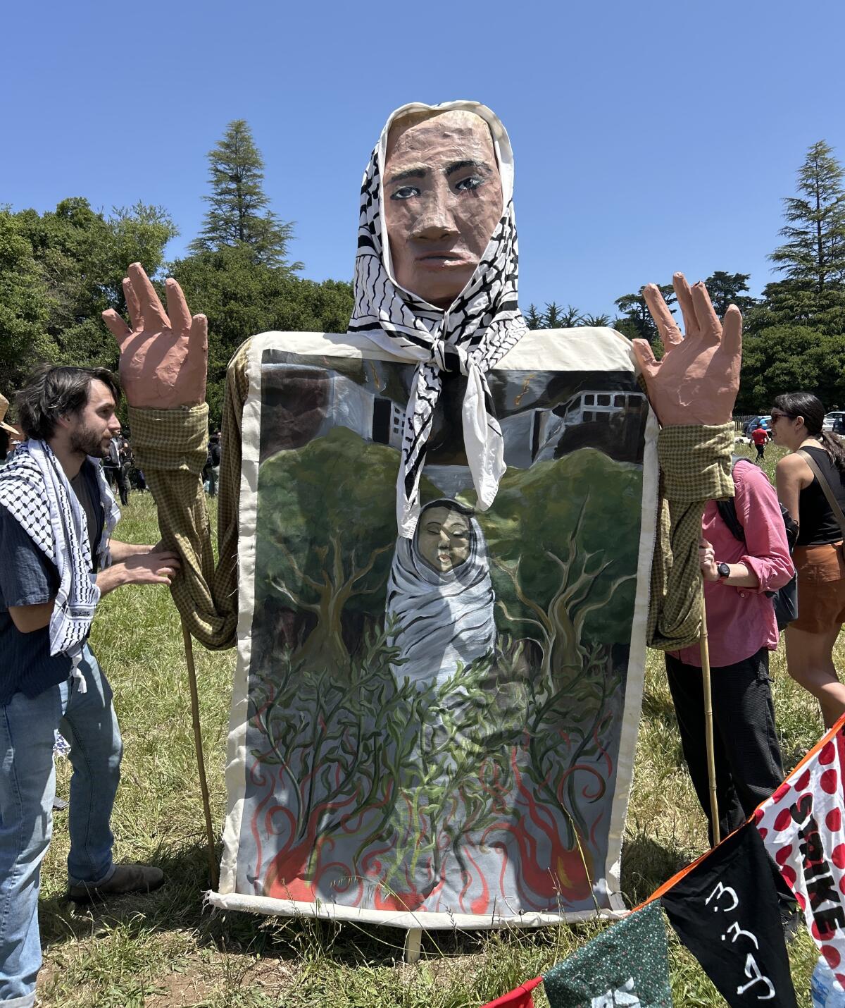 Protesters hold a puppet wearing a kaffiyeh.