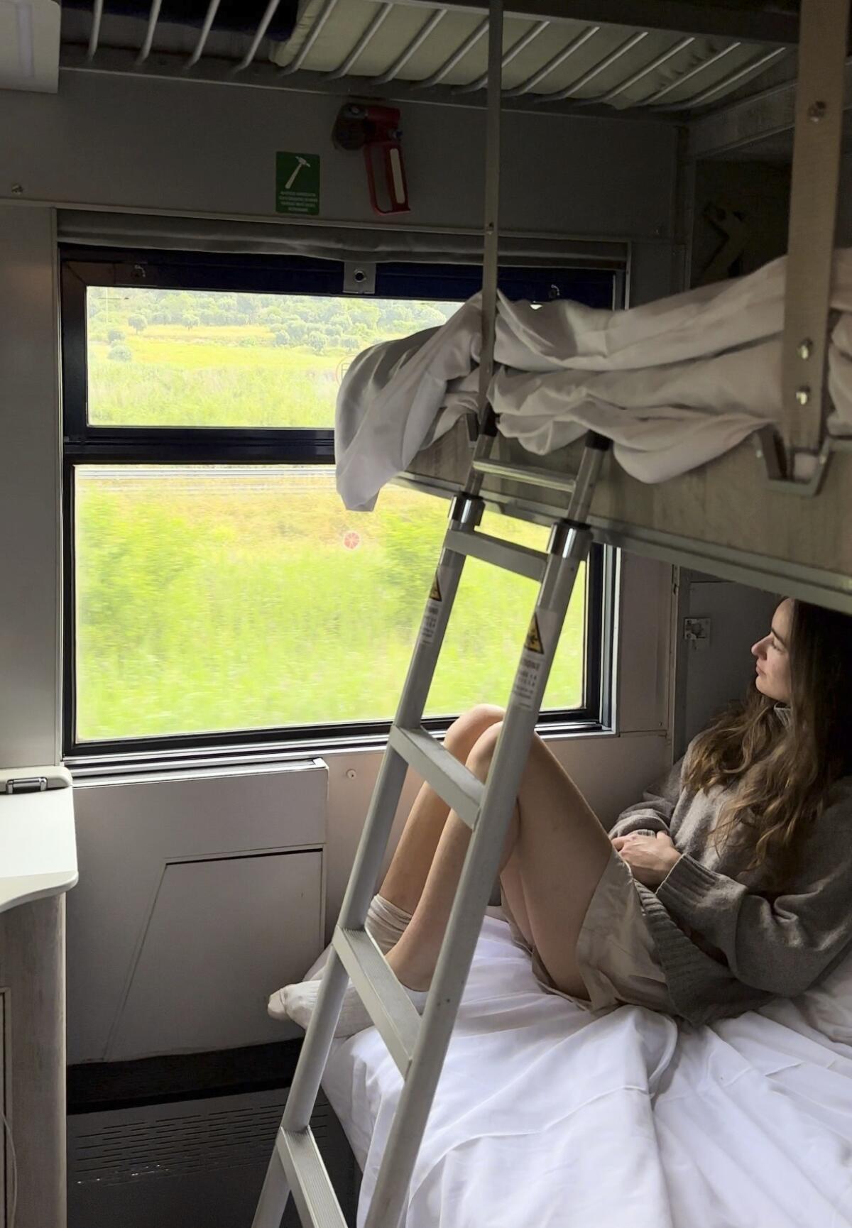 A young woman looks out at the Italian countryside on TrenItalia's Intercity Notte sleeper train from Palermo to Rome.