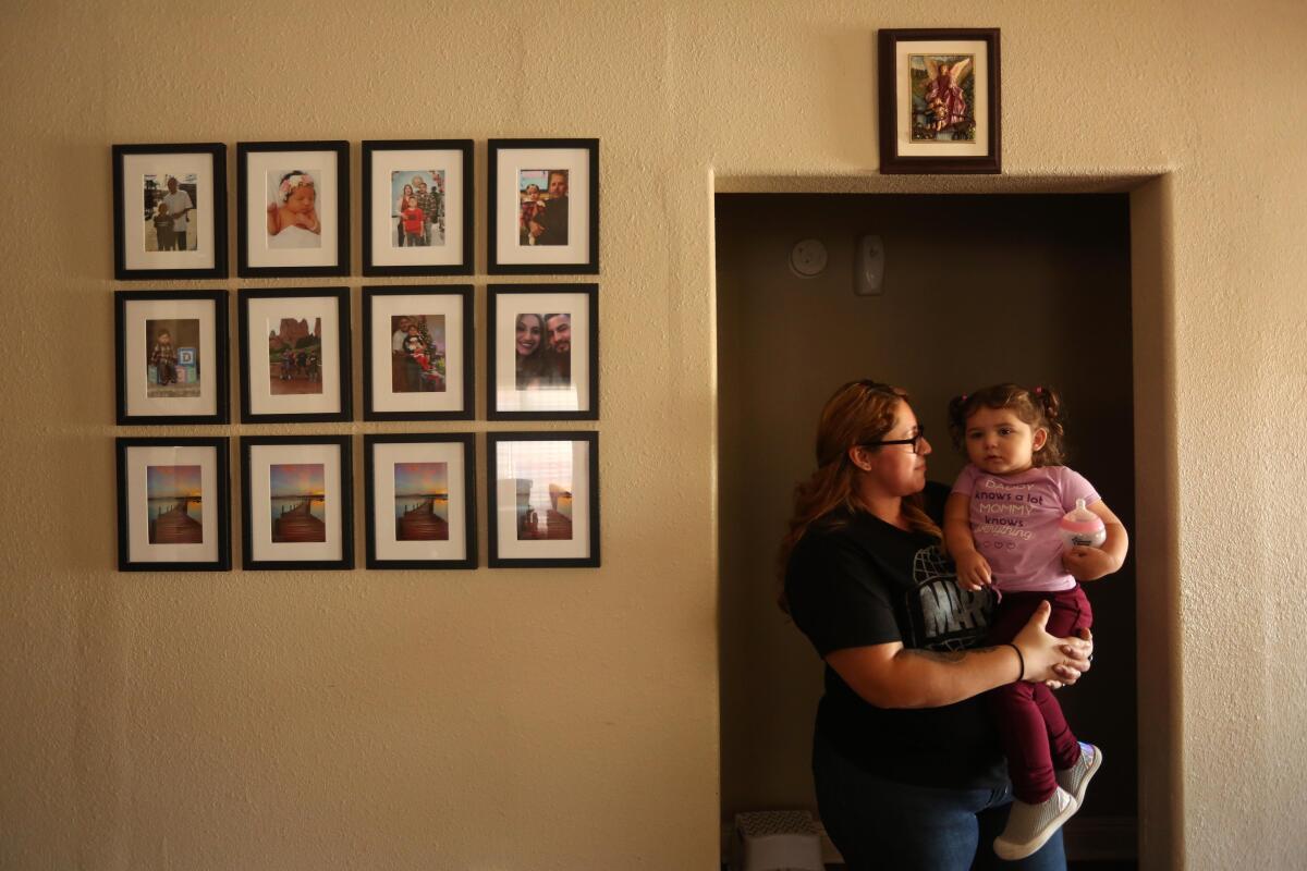 A woman holds a child in a doorway of a home.