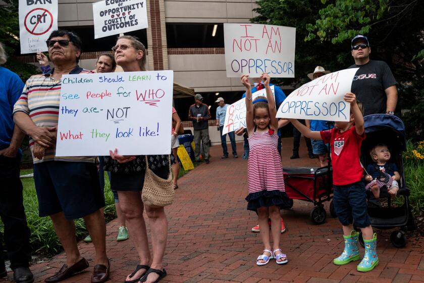 People hold up signs during a rally against "critical race theory" (CRT) being taught in schools at the Loudoun County Government center in Leesburg, Virginia on June 12, 2021. - "Are you ready to take back our schools?" Republican activist Patti Menders shouted at a rally opposing anti-racism teaching that critics like her say trains white children to see themselves as "oppressors." "Yes!", answered in unison the hundreds of demonstrators gathered this weekend near Washington to fight against "critical race theory," the latest battleground of America's ongoing culture wars. The term "critical race theory" defines a strand of thought that appeared in American law schools in the late 1970s and which looks at racism as a system, enabled by laws and institutions, rather than at the level of individual prejudices. But critics use it as a catch-all phrase that attacks teachers' efforts to confront dark episodes in American history, including slavery and segregation, as well as to tackle racist stereotypes. (Photo by ANDREW CABALLERO-REYNOLDS / AFP) (Photo by ANDREW CABALLERO-REYNOLDS/AFP via Getty Images)