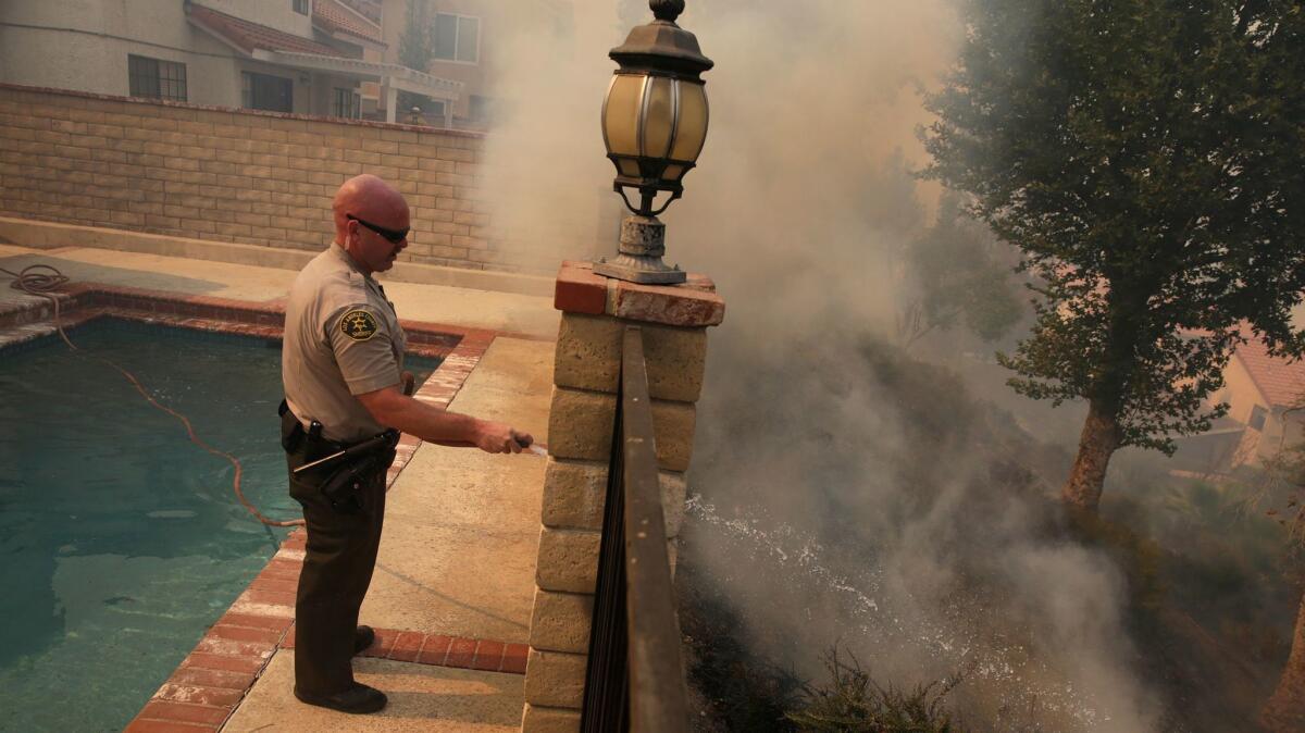 L.A. County Sheriff's Deputy Jason Viger hoses down a hot spot as fire threatens a home in Newhall.