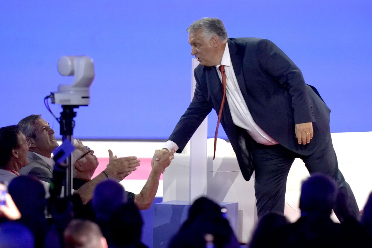 Hungarian Prime Minister Viktor Orban shakes hands from a stage
