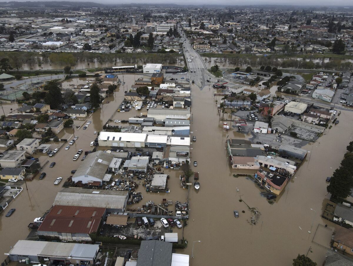An aerial view of a flooded town, with roads and yards covered with brown water
