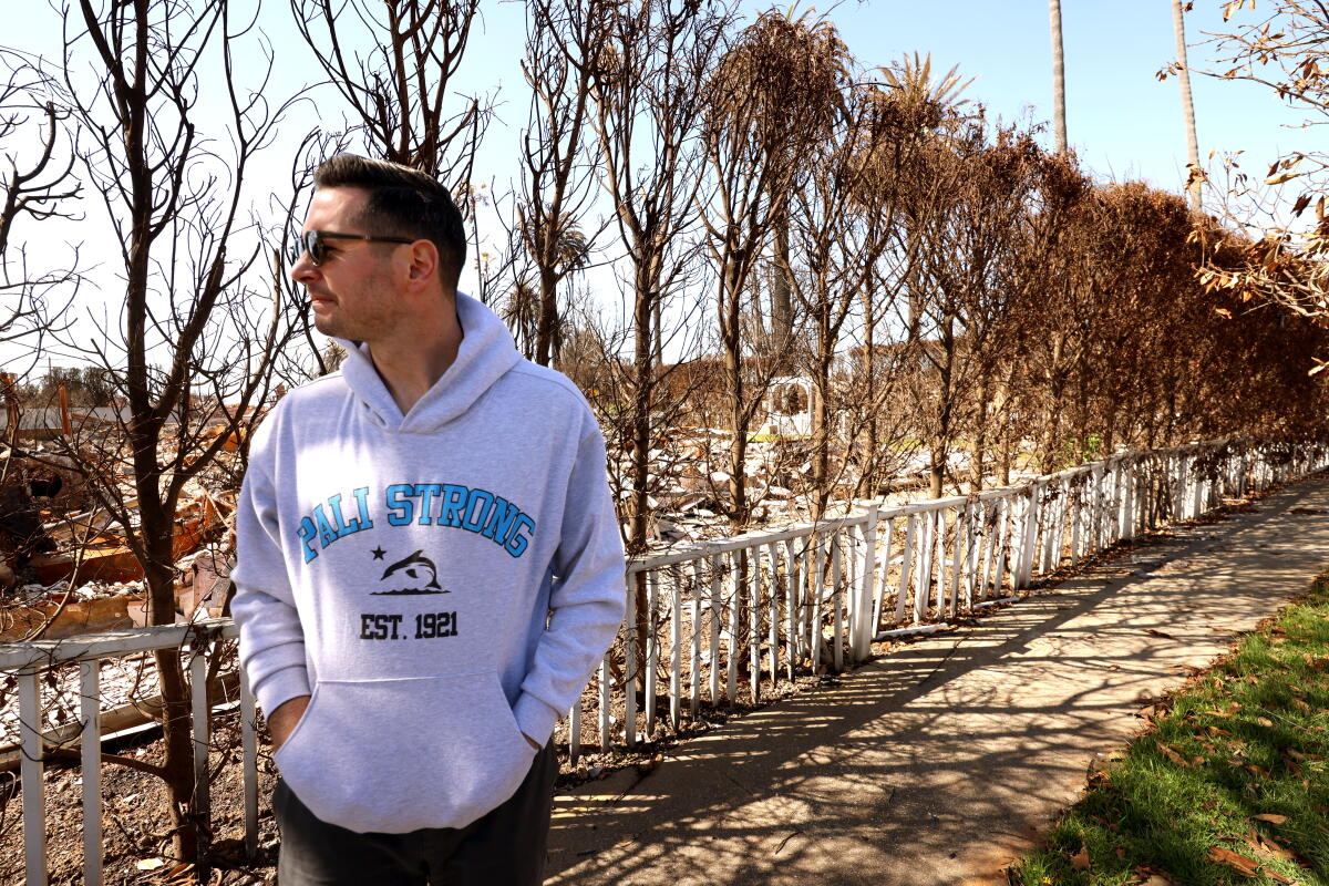 Lakers coach JJ Redick stands next to a row of charred trees where his neighbor's house once stood in Pacific Palisades.
