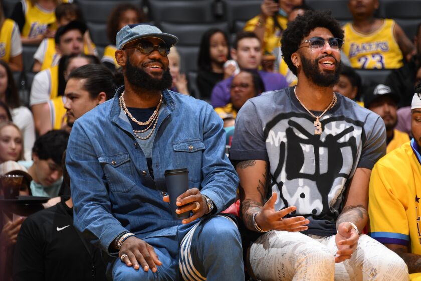 LeBron James, left, and Anthony Davis watch from the bench in street clothes as the Lakers face the Thunder on April 8, 2022.