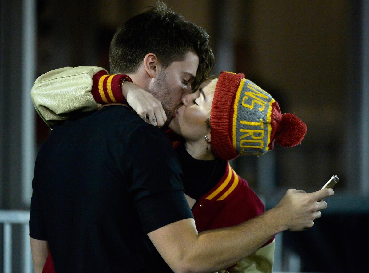 Miley Cyrus kisses Patrick Schwarzenegger during the USC-California game Thursday night at the Coliseum.