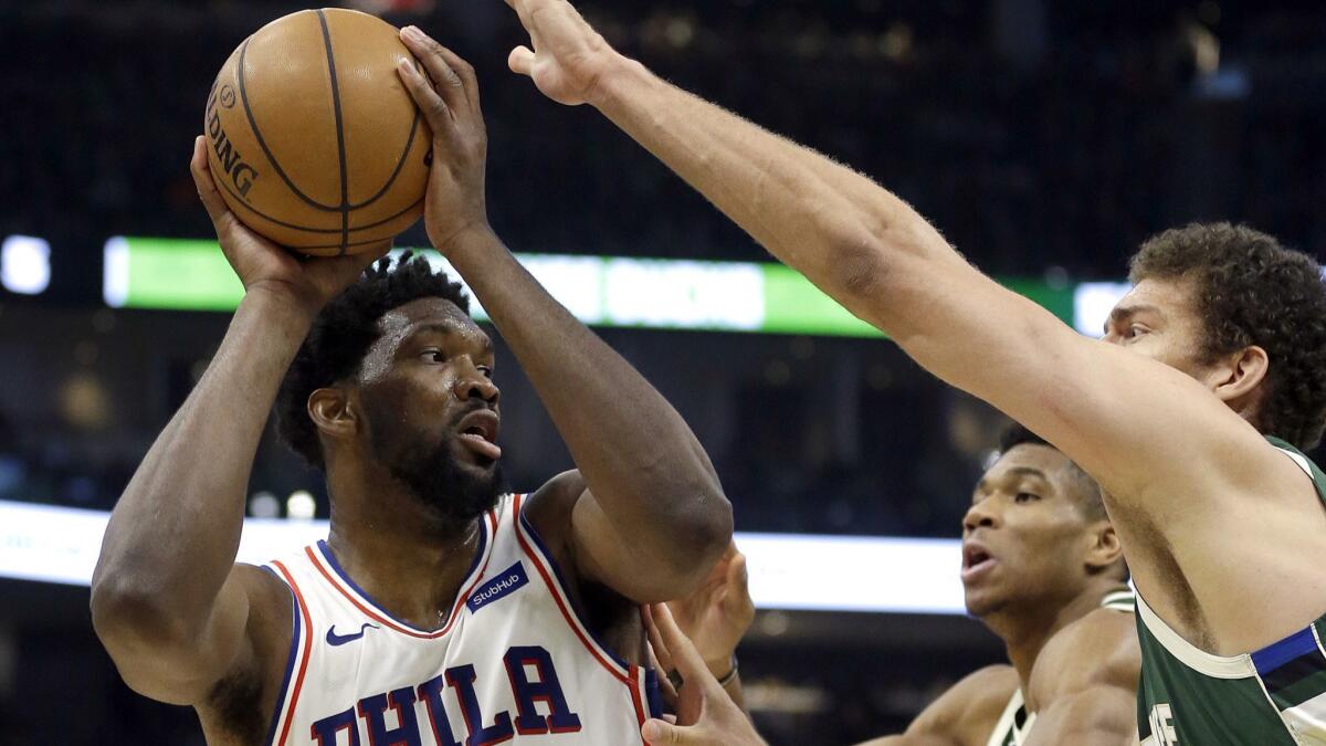 76ers center Joel Embiid faces the double-team defense of Bucks forward Giannis Antetokounmpo and center Brook Lopez during the first half Sunday.