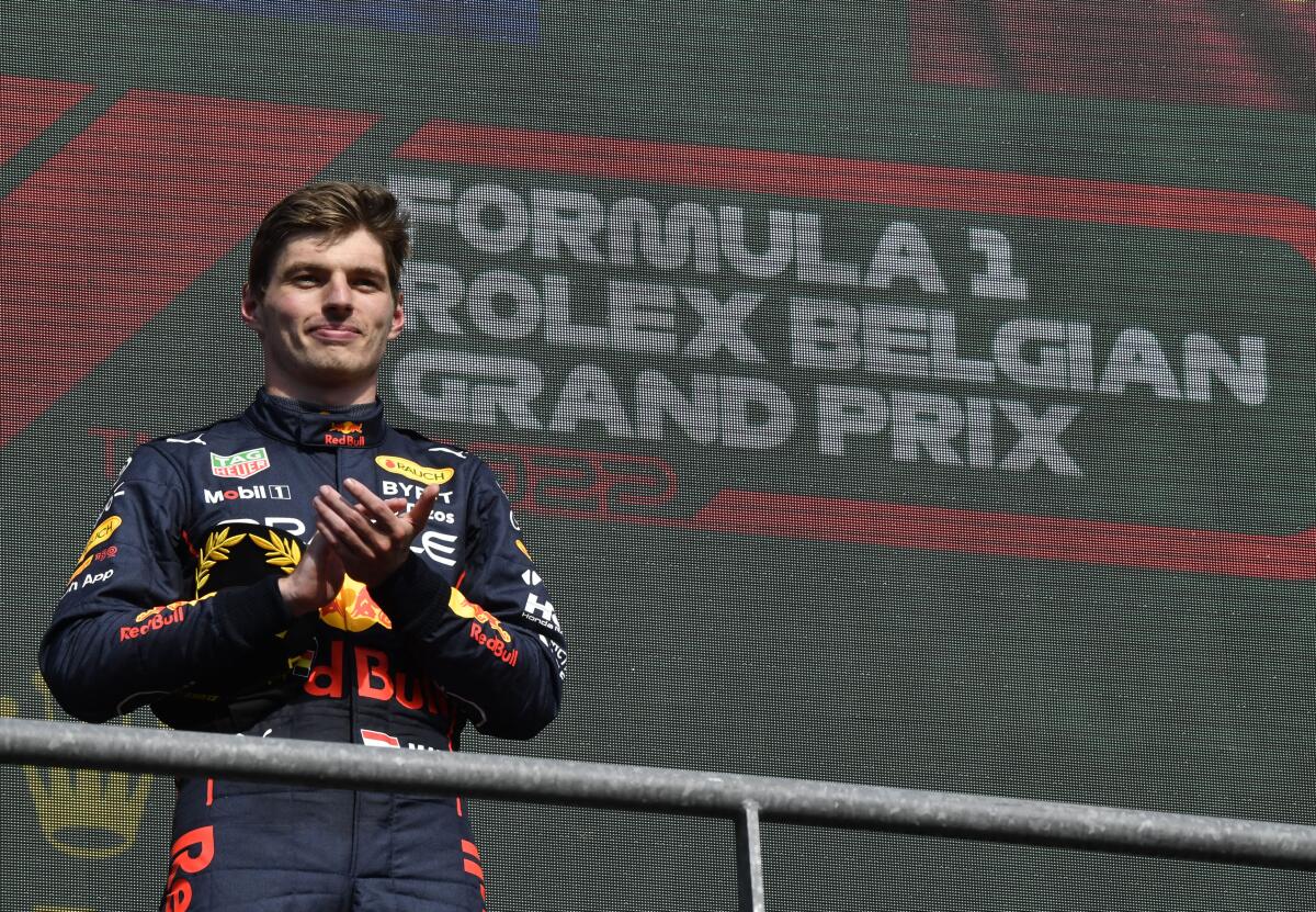 Max Verstappen applauds as he stands on the podium.