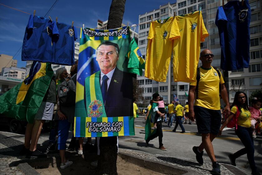 RIO DE JANEIRO, BRAZIL - SEPTEMBER 07: A flag is sold of Brazilian President Jair Bolsonaro, 67, on Brazil's Independence Day Celebration in Copacabana on Wednesday, Sept. 7, 2022 in Rio de Janeiro, Brazil. Brazilian President Jair Bolsonaro, 67, used Brazil's Independence Day Celebration to rally voters ahead of the Oct. 2nd presidential elections. Bolsanaro will be running against Luiz Inacio Lula da Silva, commonly known mononymously as Lula, a Brazilian politician and former union leader who served as the 35th president of Brazil from 2003 to 2010. (Gary Coronado / Los Angeles Times)