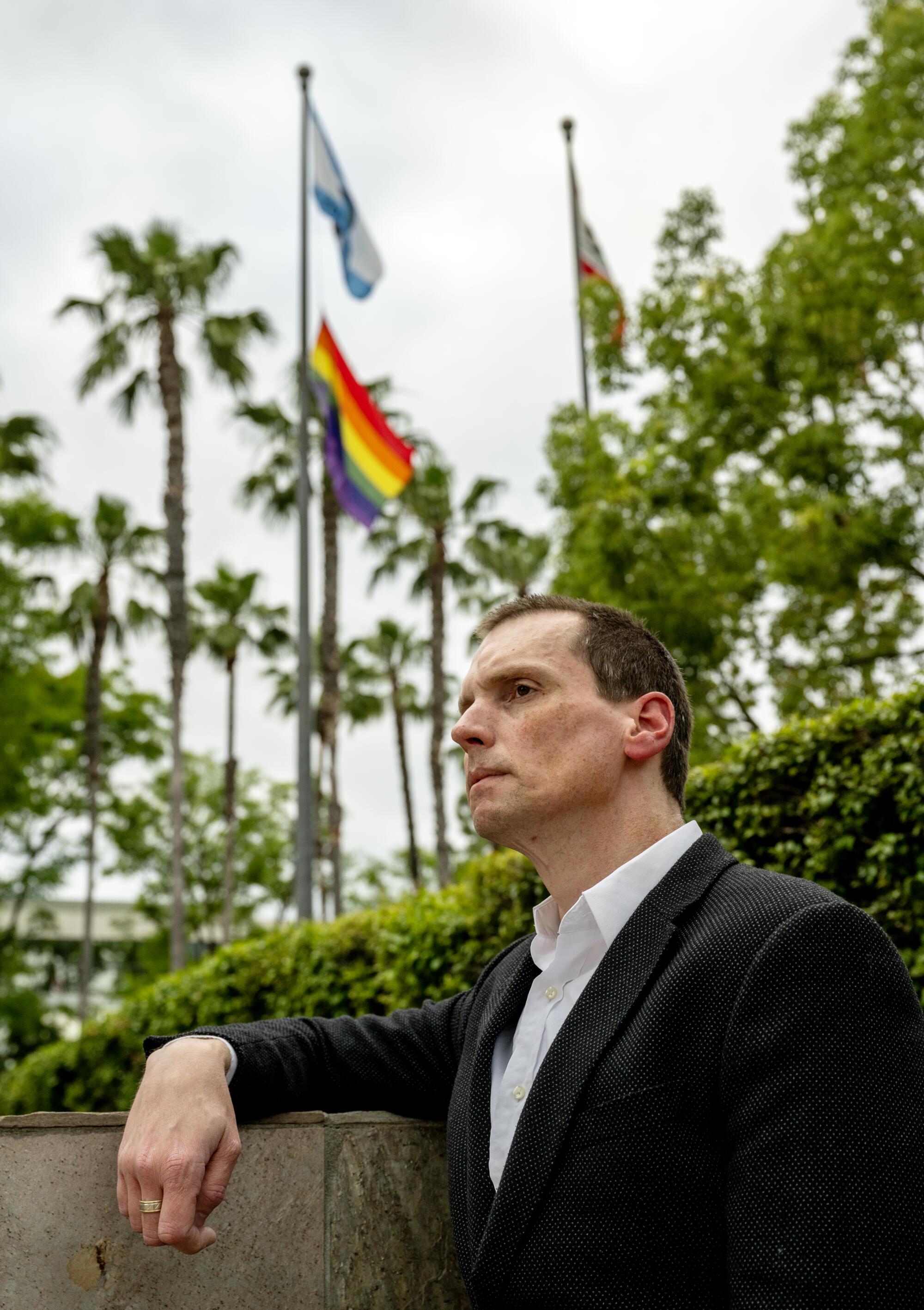 Ex-city councilman Jordan Brandman stands outside city hall near a Pride flag in Anaheim, California.