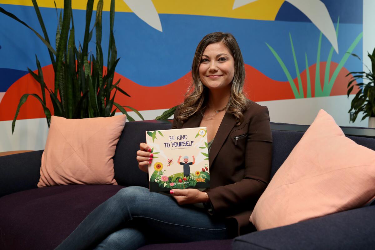 Costa Mesa resident Jeanette Knutti poses for a portrait with a copy of her children's book.