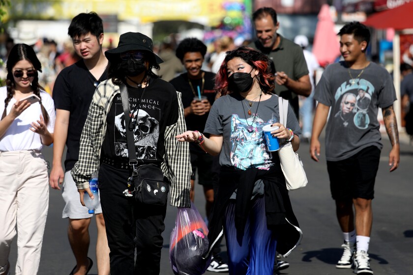 A group of people in a crowd, some masked and some unmasked