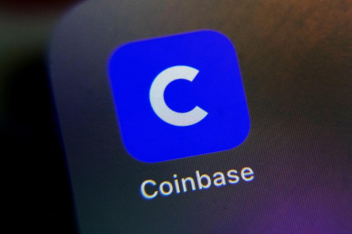 A smartphone displays the icon for the Coinbase app.
