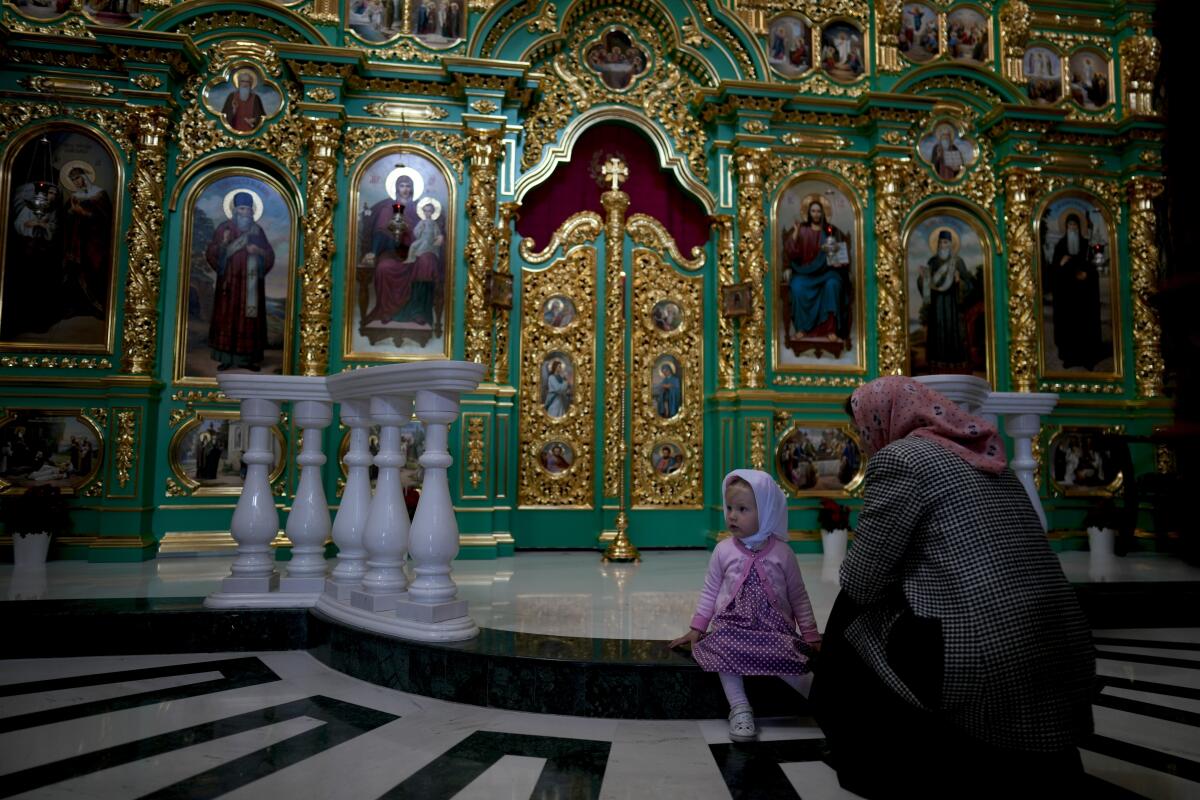 A child and woman are in front of an ornate set of paintings of Christian religious figures