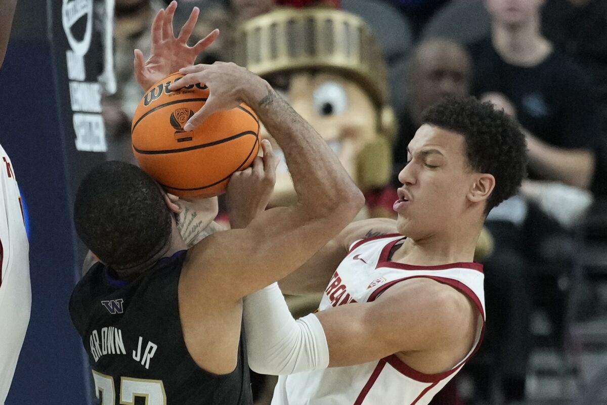 Southern California's Kobe Johnson, right, and Washington's Terrell Brown Jr. (23) battle for the ball during the first half of an NCAA college basketball game in the quarterfinal round of the Pac-12 tournament Thursday, March 10, 2022, in Las Vegas. (AP Photo/John Locher)