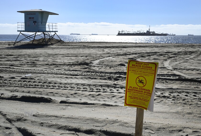 The release of 2 million to 4 million gallons of untreated sewage into the Dominguez Channel in Carson, Calif. on Friday, Dec. 31, 2021, has forced the closures of some beaches. This beach closure sign posted at the Granada Beach boat launch ramp was the only sign posted before 1 p.m. (Brittany Murray/The Orange County Register via AP)