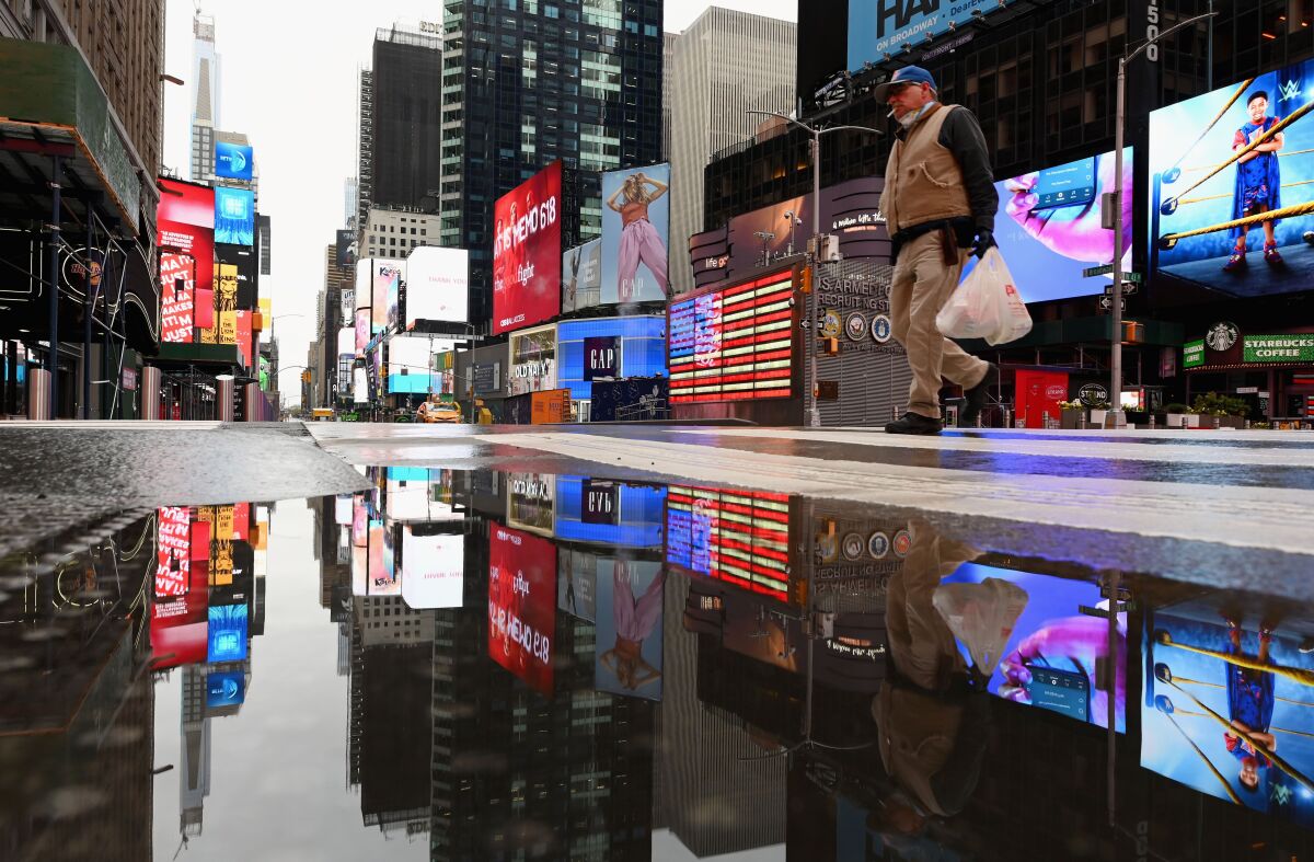 A man crosses the street at a nearly empty Times Square on Thursday in New York City. 