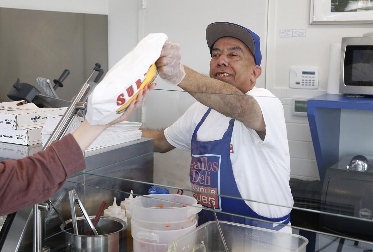 Longtime Gallo's employee Jose Andrade hands a sandwich to a customer.